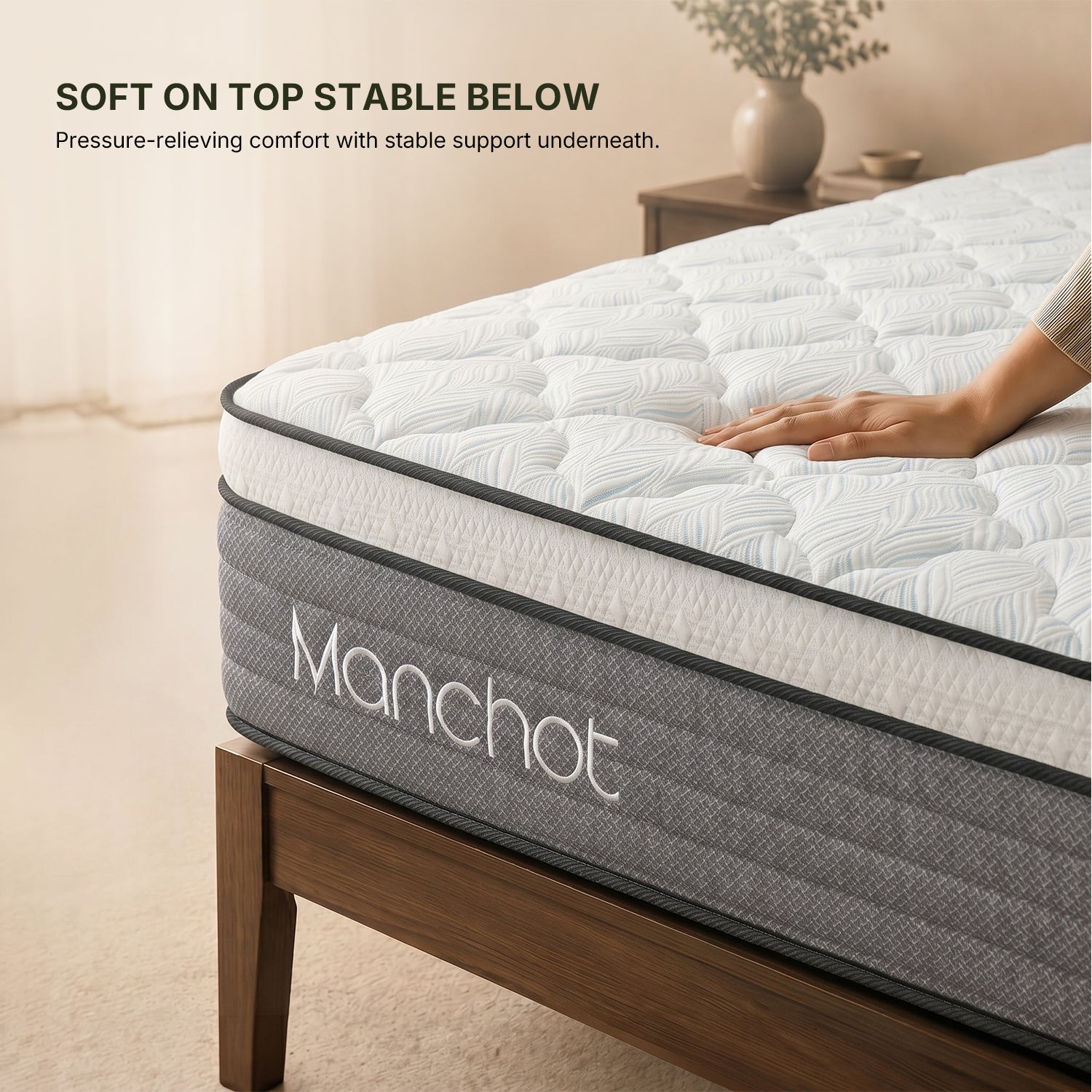 hand pressing manchot hybrid mattress showing plush quilted comfort layer with stable support underneath