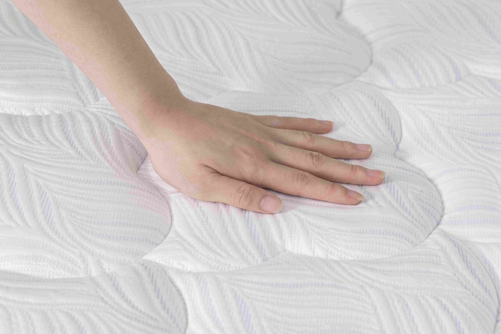 A hand moving across the finished mattress surface.